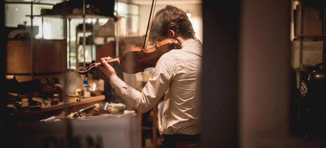 photo from behind a man as he plays the violin