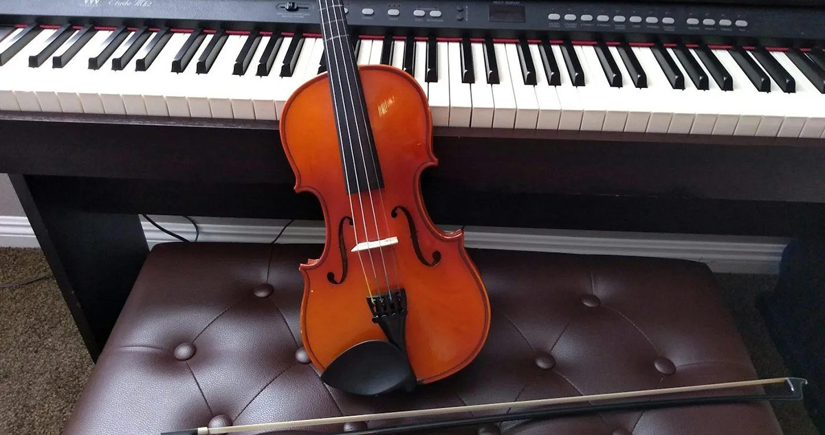 Violin lying on a bench next to a piano