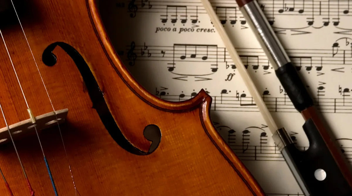 Closeup of a violin and bow on top of a sheet of music